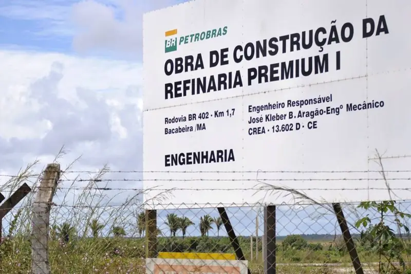 Placa da obra de construção da Refinaria Premium I, atrás de uma cerca de arame, em Bacabeira